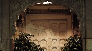 A grand entrance with a large ornate door, flanked by potted plants. - Aakash Heritage Haveli (Jodhpur)