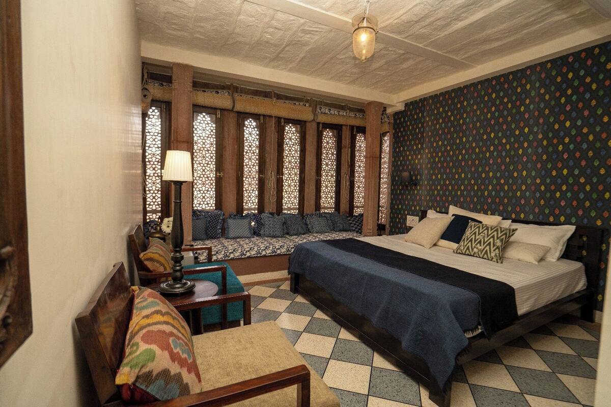 A room with a bed, a sofa, a chair, and a table.