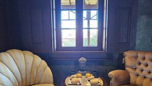 Una stanza con due poltrone imbottite, un tavolo in legno con prodotti per la colazione e una finestra vista verde.