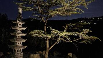 Uma pagoda japonesa tradicional com uma árvore em primeiro plano, contra um céu noturno com a lua visível.