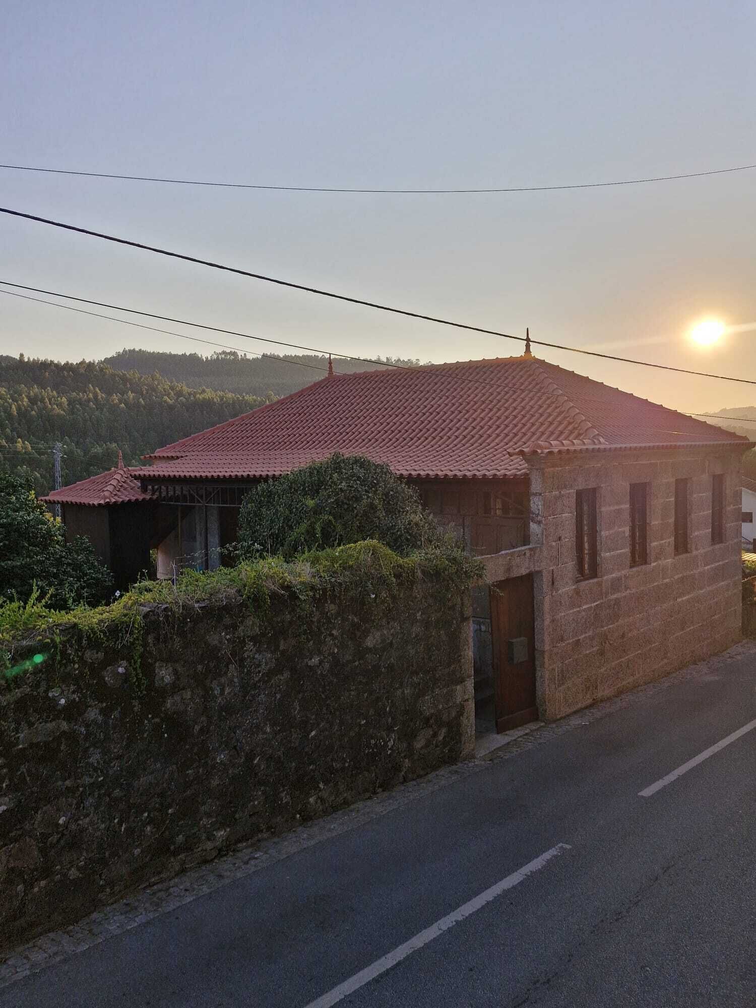 Ein Gebäude mit rotem Ziegeldach, einer Steinmauer und einer Straße davor.