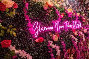 A neon sign with the text 'Zlanna Never Again' surrounded by flowers and foliage.