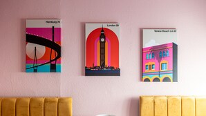 A hotel room with three wall art pieces depicting landmarks from Hamburg, London, and Venice Beach.