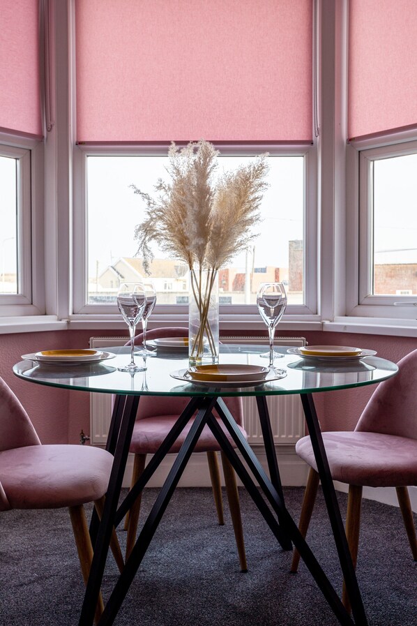 A dining table with two chairs, a vase with dried plants, and two wine glasses.
