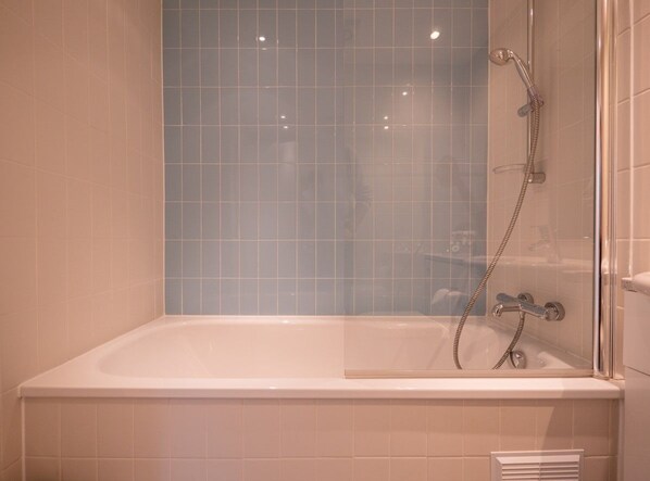 A bathroom with a bathtub, a shower, and a glass-enclosed shower area.