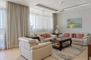 A modern living room with a sofa set, a coffee table, and a painting on the wall.