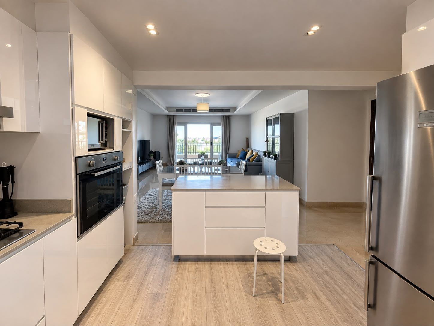 A modern kitchen with a central island, stainless steel appliances, and a view to a balcony.