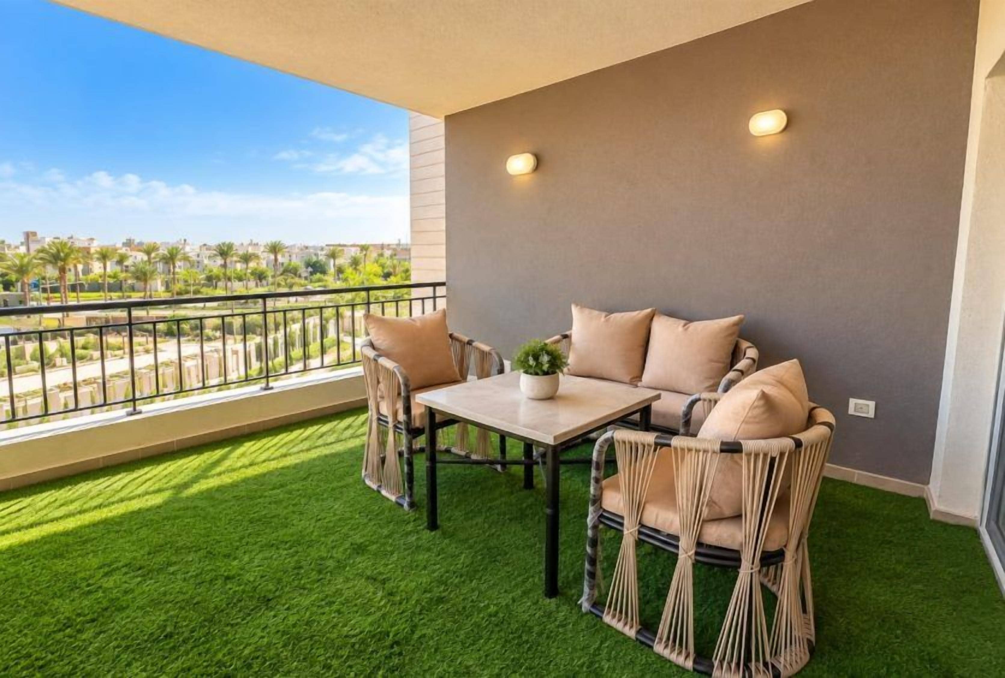 Un balcon avec une table et des chaises, un pot de fleurs et une vue sur le paysage urbain.