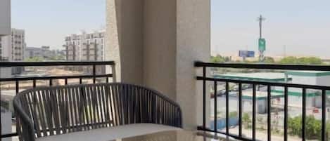 A balcony with a glass table and chairs, a view of the city, and a railing.
