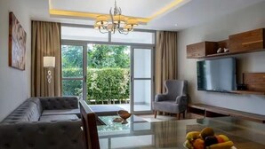 A modern living room with a sofa, armchair, glass coffee table, and a fruit bowl. - VESTA - Cairo Festival City Residence (New Cairo)