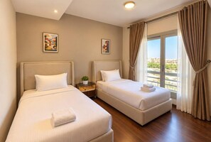 A hotel room with two beds, a small table with a plant, and a view of the city through large windows. - VESTA - Cairo Festival City Residence (New Cairo)