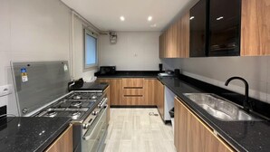 A modern kitchen with a gas stove, oven, and black countertops. - VESTA - Cairo Festival City Residence (New Cairo)