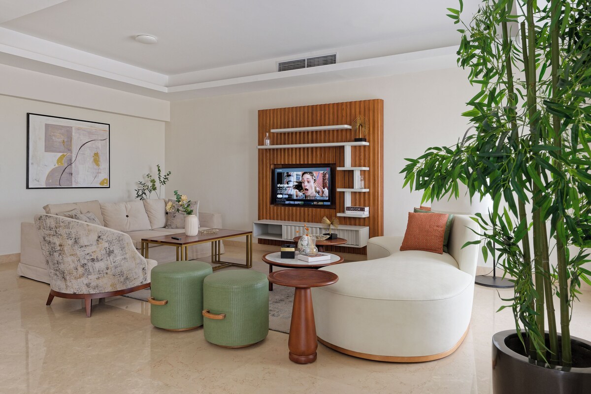 A modern living room with a sofa, armchairs, a coffee table, and a television.