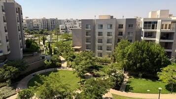 A residential complex with multiple apartment buildings, landscaped gardens, and a clear sky.