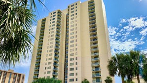 A tall beige hotel with multiple balconies, surrounded by palm trees and a clear sky. - Brighton 107 2 Br in Kingston Beach, Pool (Myrtle Beach)