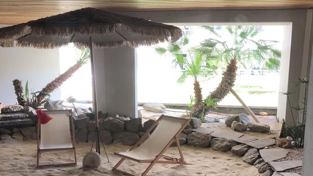 A beachside lounge area with a thatched umbrella, two lounge chairs, and a sandy floor with scattered rocks. - SEAFRONT: T2 * * * , GARAGE, AIR-CONDITIONING, WI-FI (Frejus)