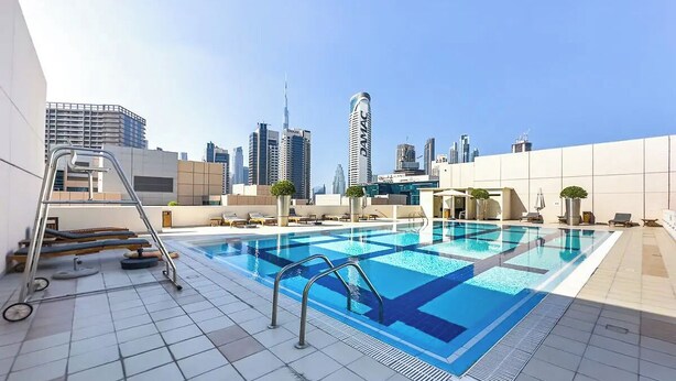 A rooftop swimming pool with a city skyline in the background.