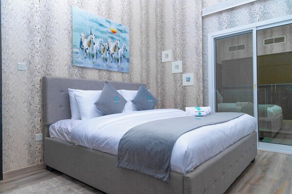 A bedroom with a bed, a painting, and a sliding glass door.