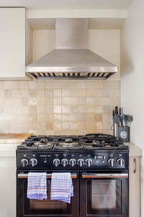 A kitchen with a gas stove, oven, and a stainless steel range hood.