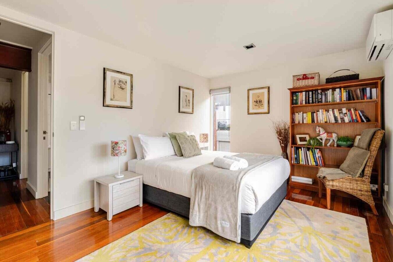 Une chambre à coucher avec un lit, des tables de chevet, une bibliothèque et une chaise.