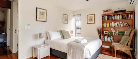 A bedroom with a bed, bedside tables, a bookshelf, and a chair.