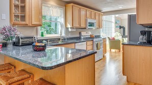 A modern kitchen with wooden cabinets, granite countertops, and a central island. - 1/2 Mi to Ogunquit Beach: Maine Home w/ Deck! (Ogunquit)