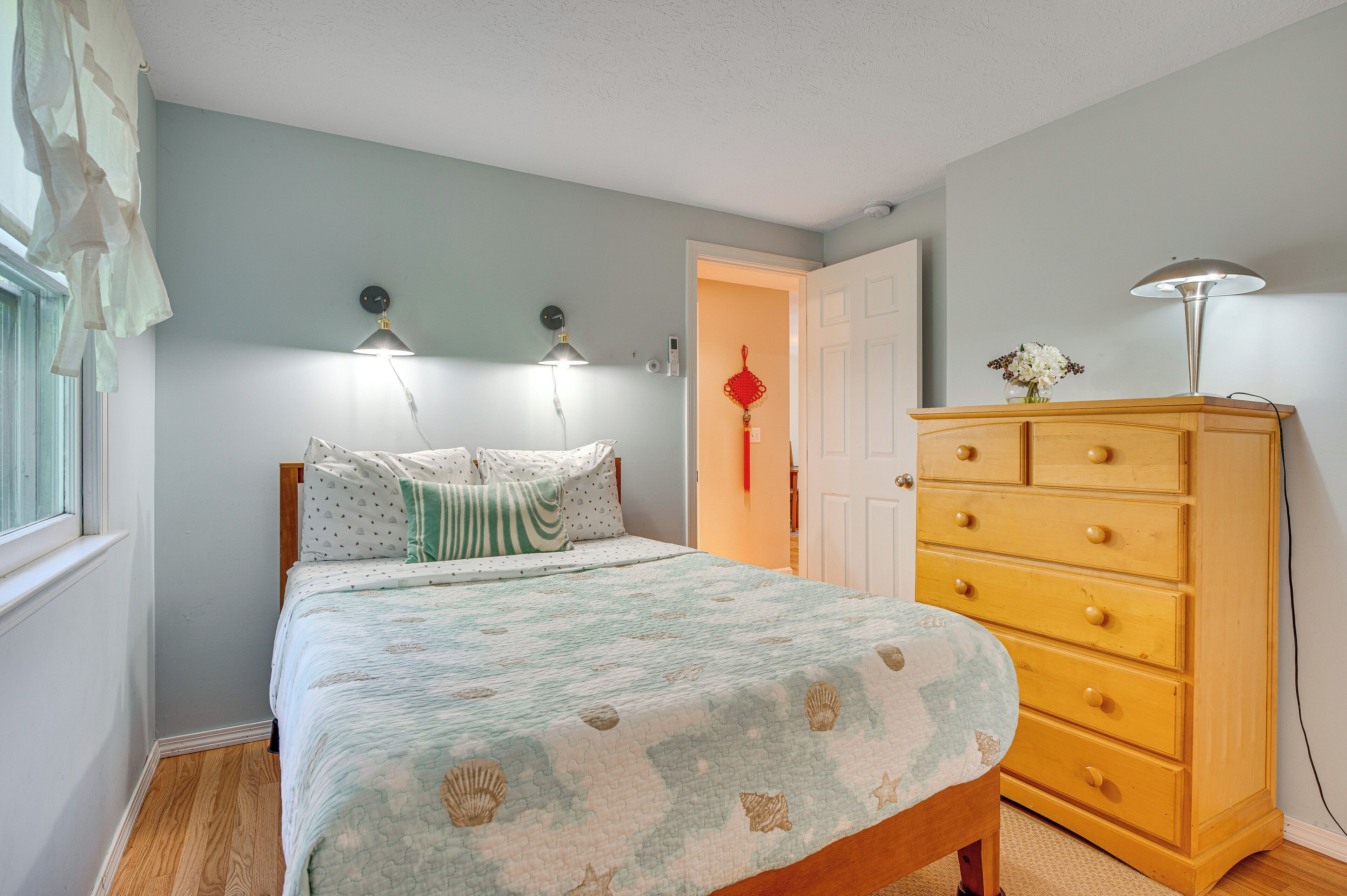 A bedroom with a bed, bedside lamps, a dresser, and a door.
