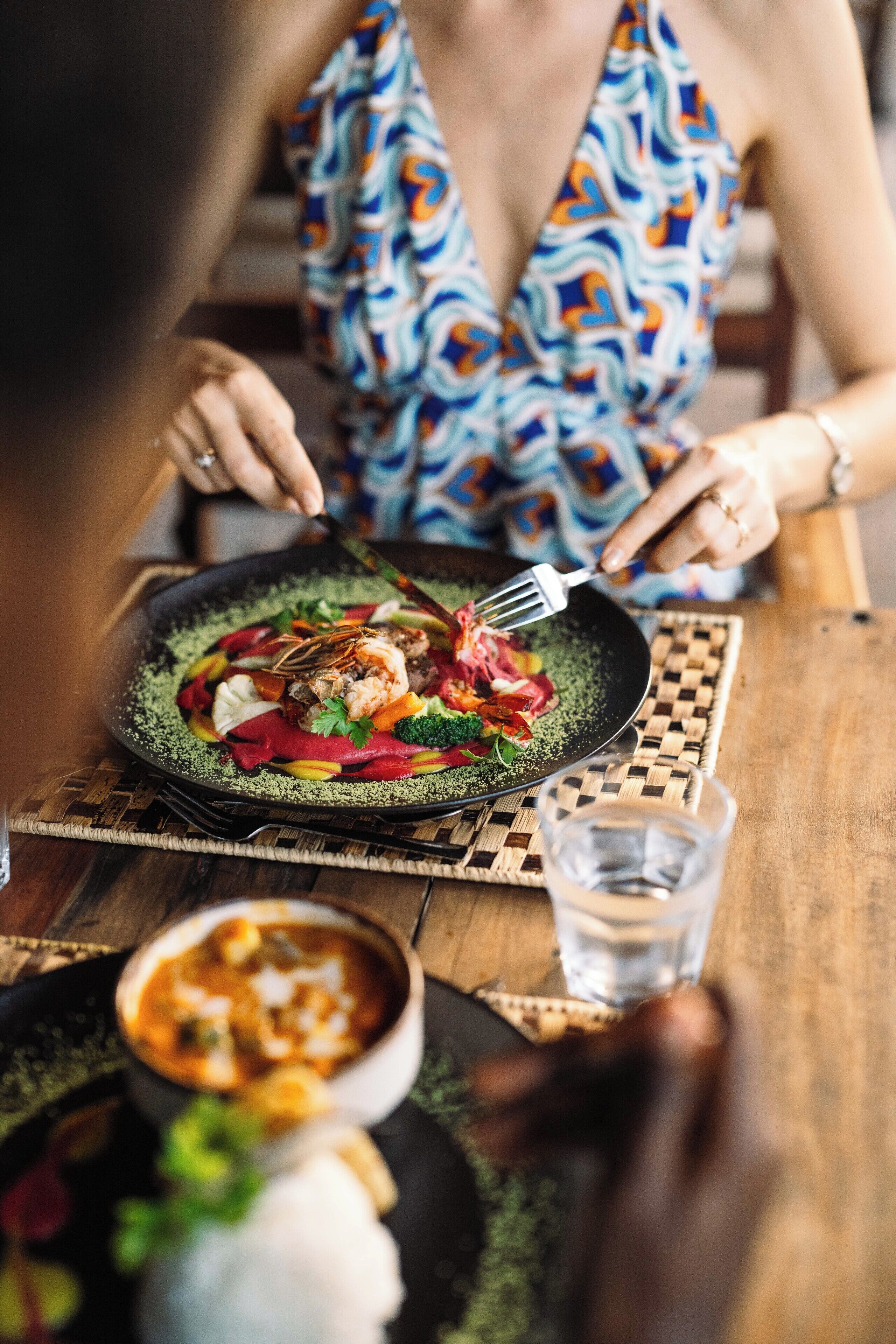 A dining table with a plate of food, a fork, and a glass of water.
