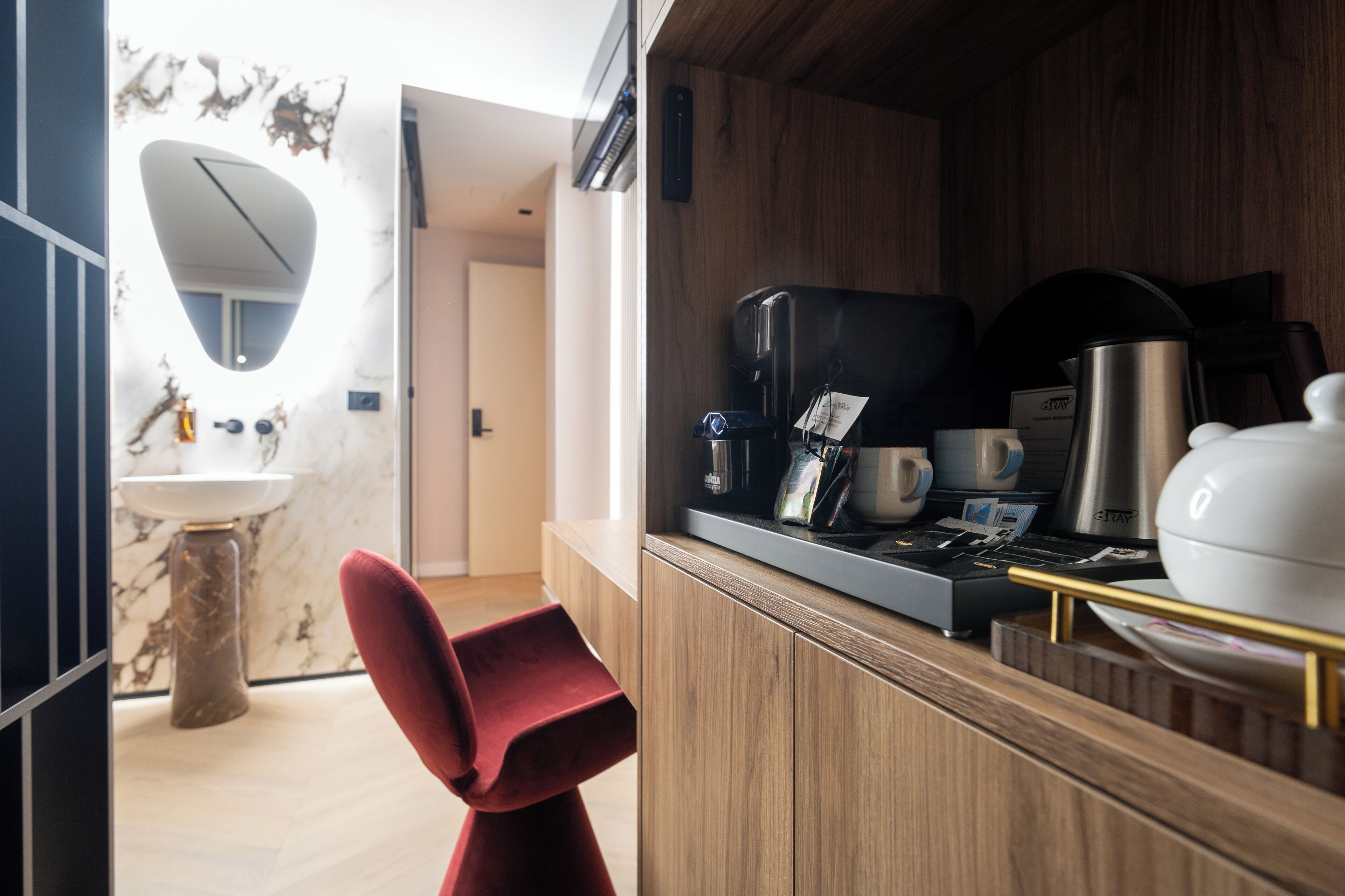 A modern kitchen with a wooden cabinet, a marble countertop, and a red chair.