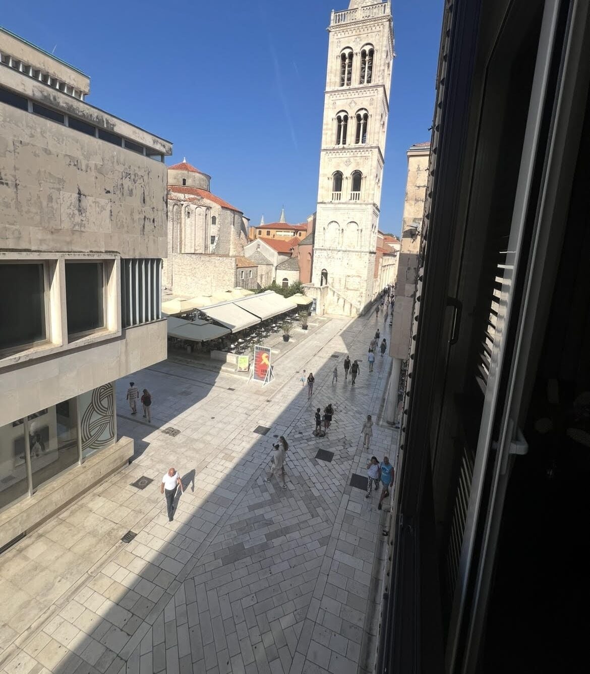 A courtyard with a historic tower, paved walkways, and a mix of architectural styles.