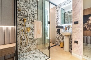 Un bagno moderno con pareti in marmo, box doccia in vetro, mobile lavabo e un grande specchio.