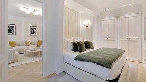 Une chambre moderne avec un grand lit, un canapé et une table basse. On y trouve également une armoire et un luminaire fixé au mur.