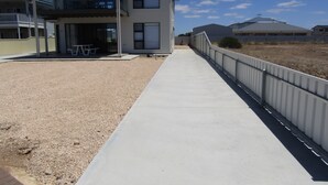 A two-story building with a balcony, a concrete walkway, and a fenced area. - Zion on Yorkes-2 bedroom downstairs unit - Off peak special! (Edithburgh)