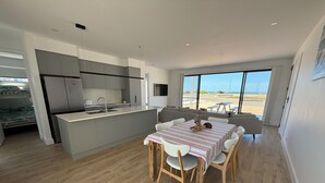 A modern kitchen with grey cabinets, a stainless steel refrigerator, and a dining area with a table and chairs. - Zion on Yorkes-2 bedroom downstairs unit - Off peak special! (Edithburgh)