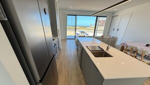 A modern kitchen with a large island, stainless steel appliances, and a view of the beach through the sliding glass doors. - Zion on Yorkes-2 bedroom downstairs unit - Off peak special! (Edithburgh)