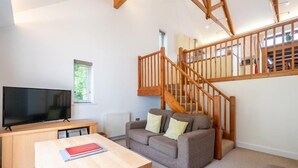 A living room with a TV, wooden table, sofa, and a staircase.