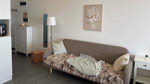 A modern living room with a sofa, a lamp, a framed artwork, and a small table with a plant. - Residence Hills Lux Hotels & Spa Kopaonik (Raška)
