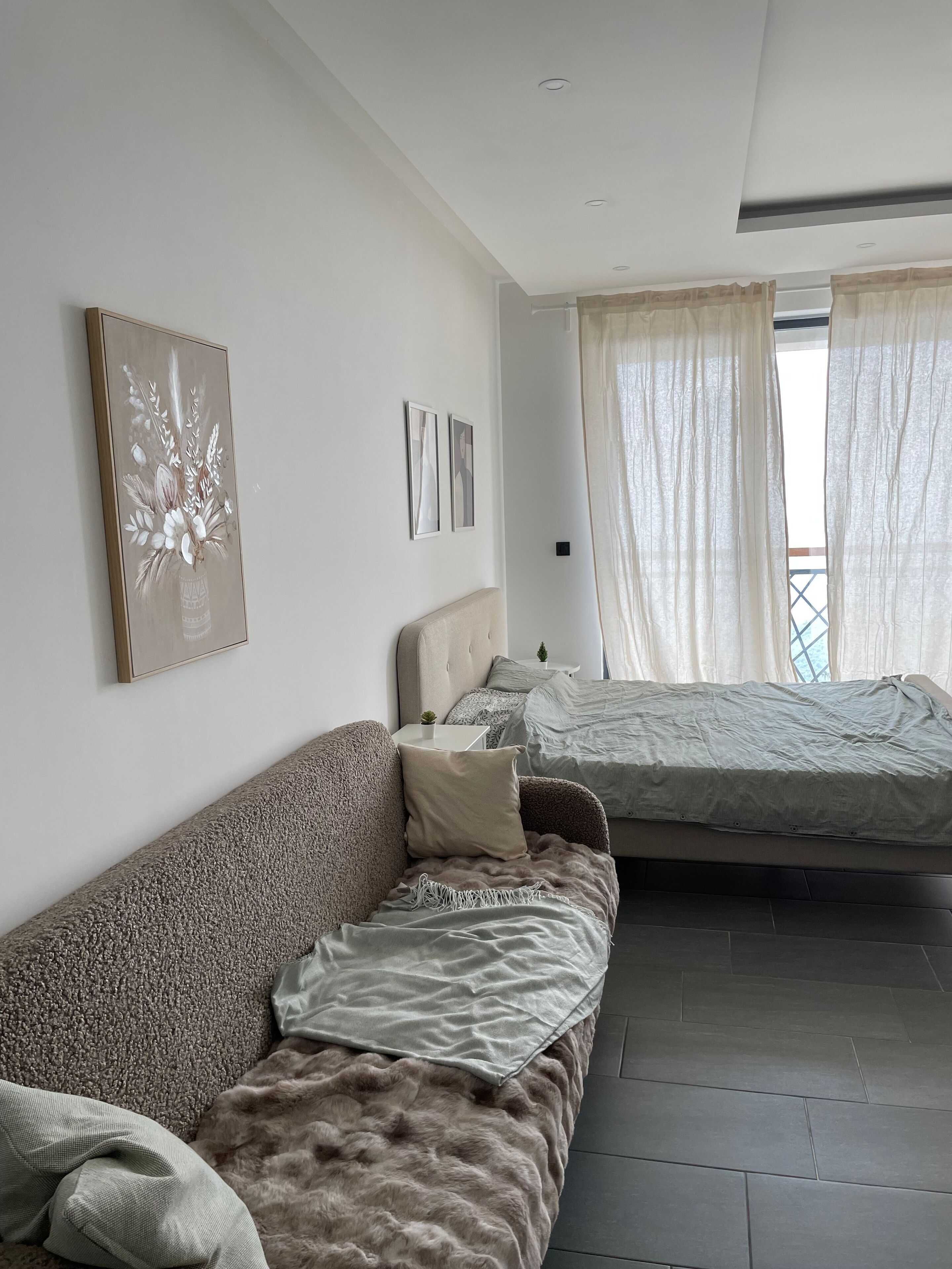 Un dormitorio moderno con un sofá, una cama y una mesita con una planta.