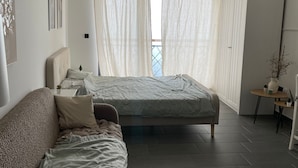 A modern bedroom with a sofa, a bed, a wardrobe, and a small table with a plant. - Residence Hills Lux Hotels & Spa Kopaonik (Raška)