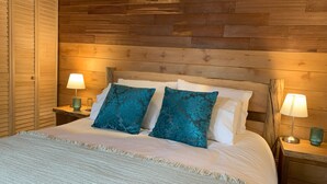 A bed with two pillows, two bedside lamps, and a wooden headboard. - Cumbres de Chiloé (Castro)