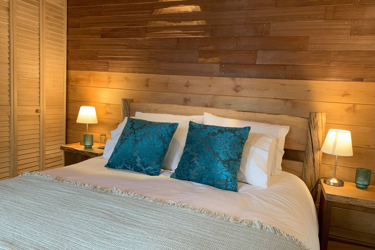 Ein Bett mit zwei Kissen, zwei Nachttischlampen und einem Holzkopfteil.
