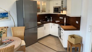 A compact kitchen with white cabinets, a stainless steel refrigerator, a microwave, and a wooden countertop. - Comfortable, fully equipped vacation apartment with terrace and garden access (List)