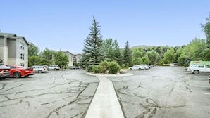 Un parking avec plusieurs voitures, une allée centrale et de la verdure tout autour.