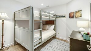 A bunk bed room with a desk and lamp, a framed map on the wall, and a small plant on the desk. - River Pines A303 3 Bedroom Condo (Edwards)