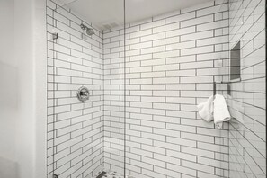 Een douchehoek met witte wandtegels en een handdoek aan de muur.
