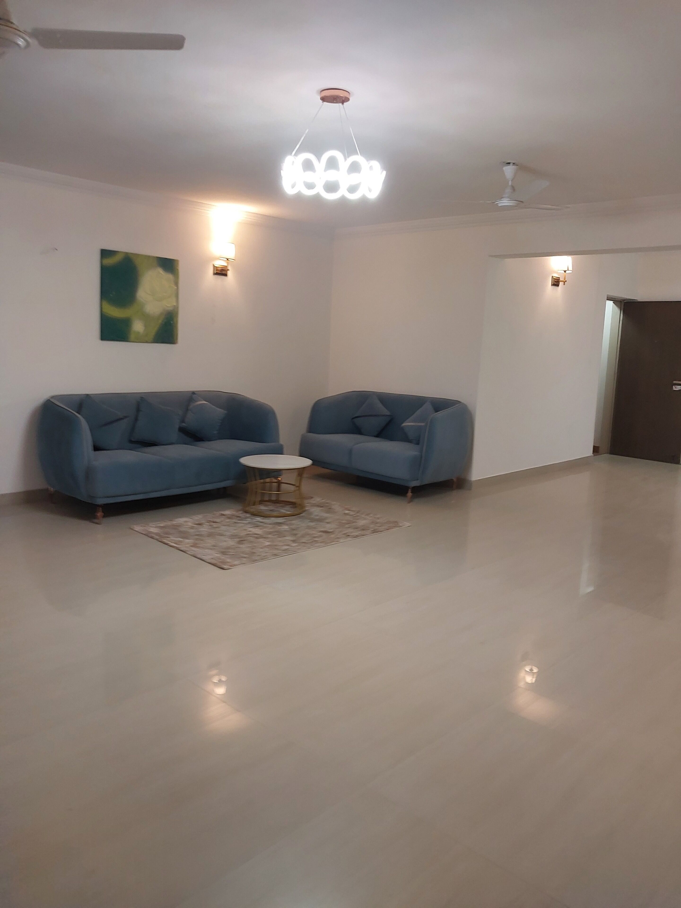 A spacious living room with two sofas, a small round coffee table, and a modern ceiling light fixture.