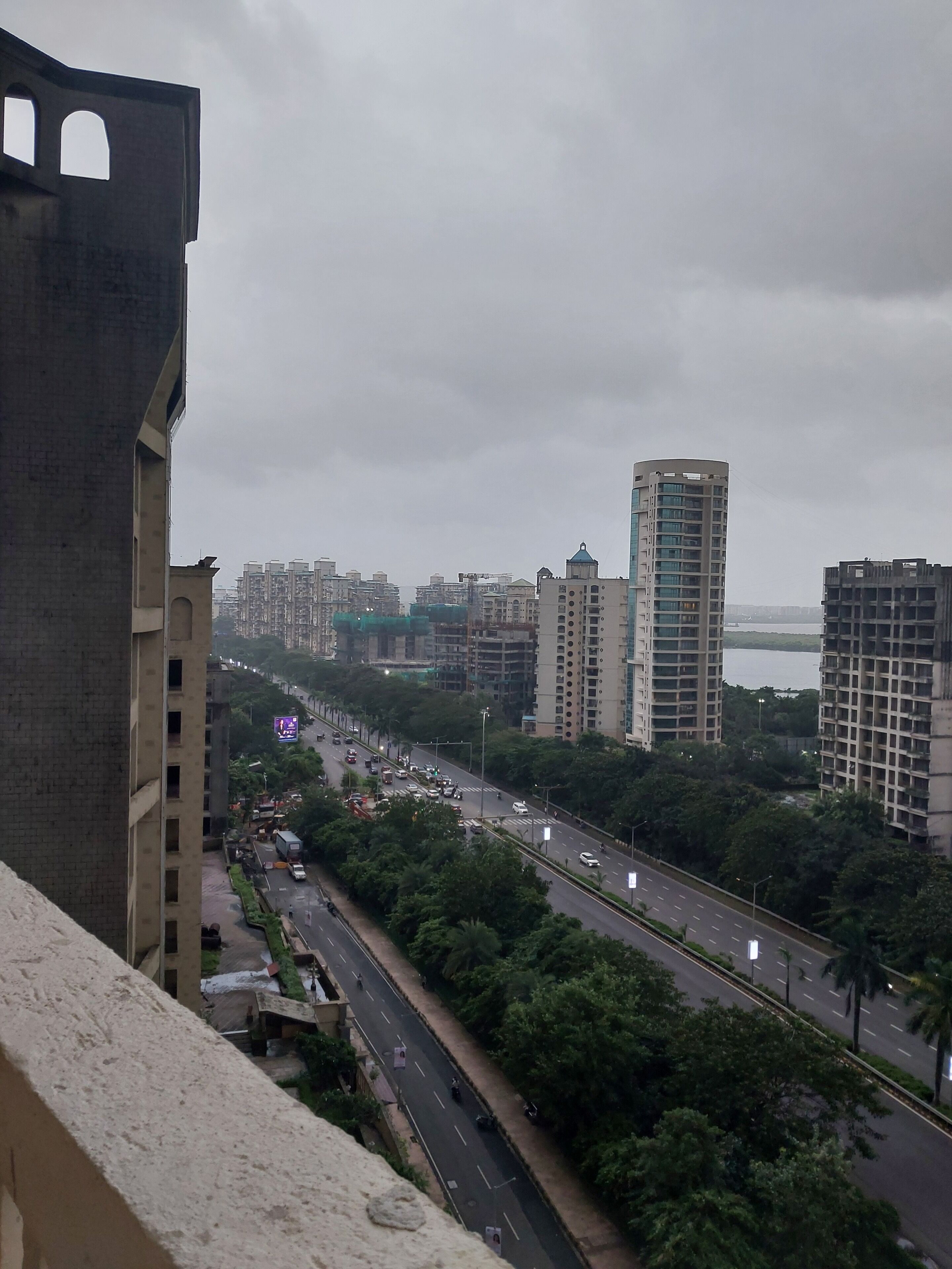 A cityscape with high-rise buildings, a busy road, and a body of water in the distance.