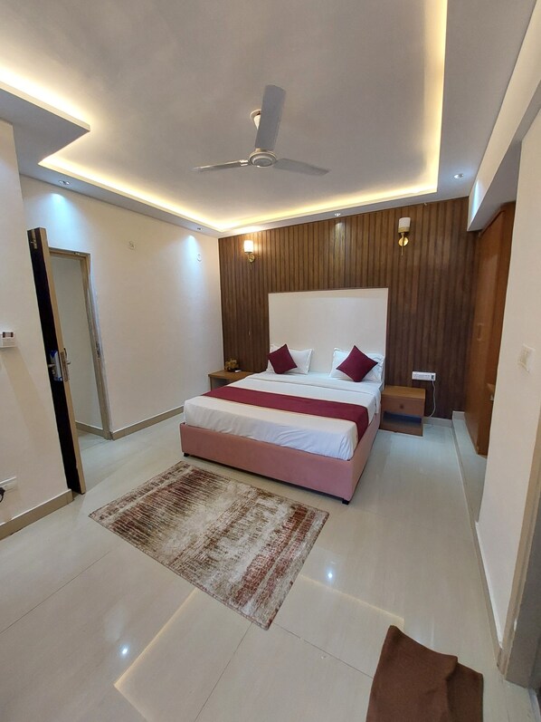 A modern bedroom with a large bed, a ceiling fan, and a nightstand. - Outstay Executive Apartments (Navi Mumbai)