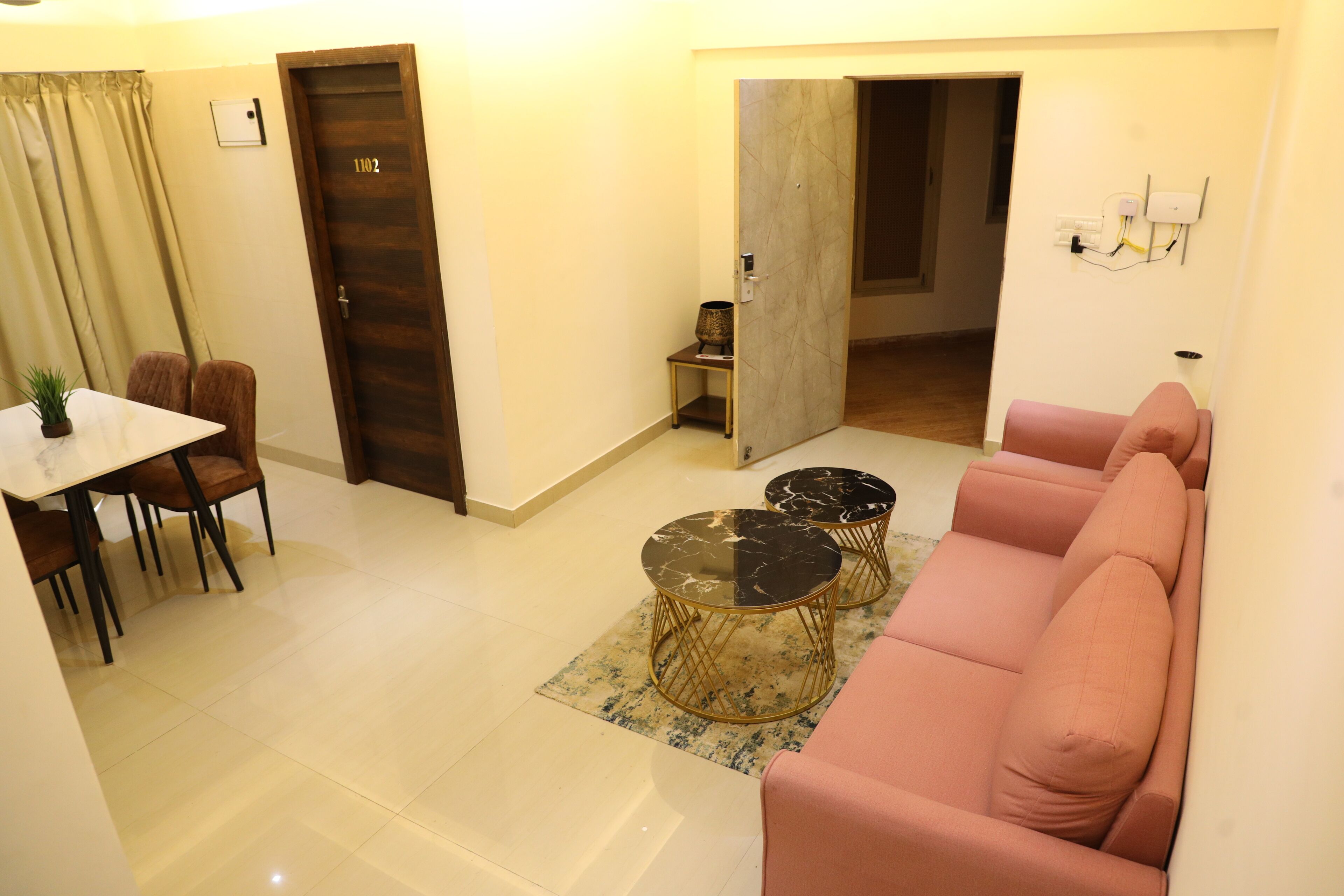 A living room with a sofa, a dining table with chairs, and two small round tables.