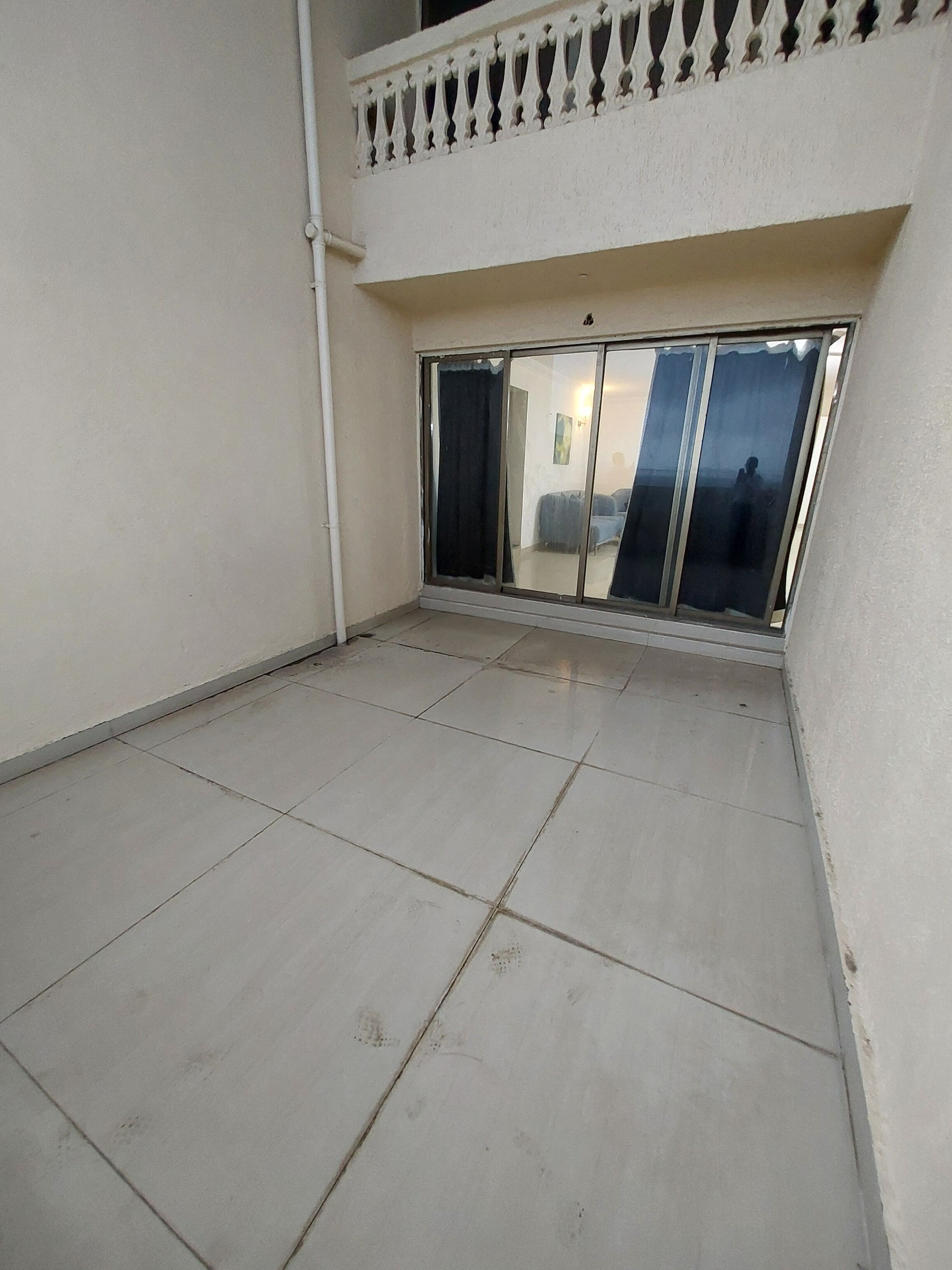 Uma varanda com piso de azulejos e guarda-corrimão branco.